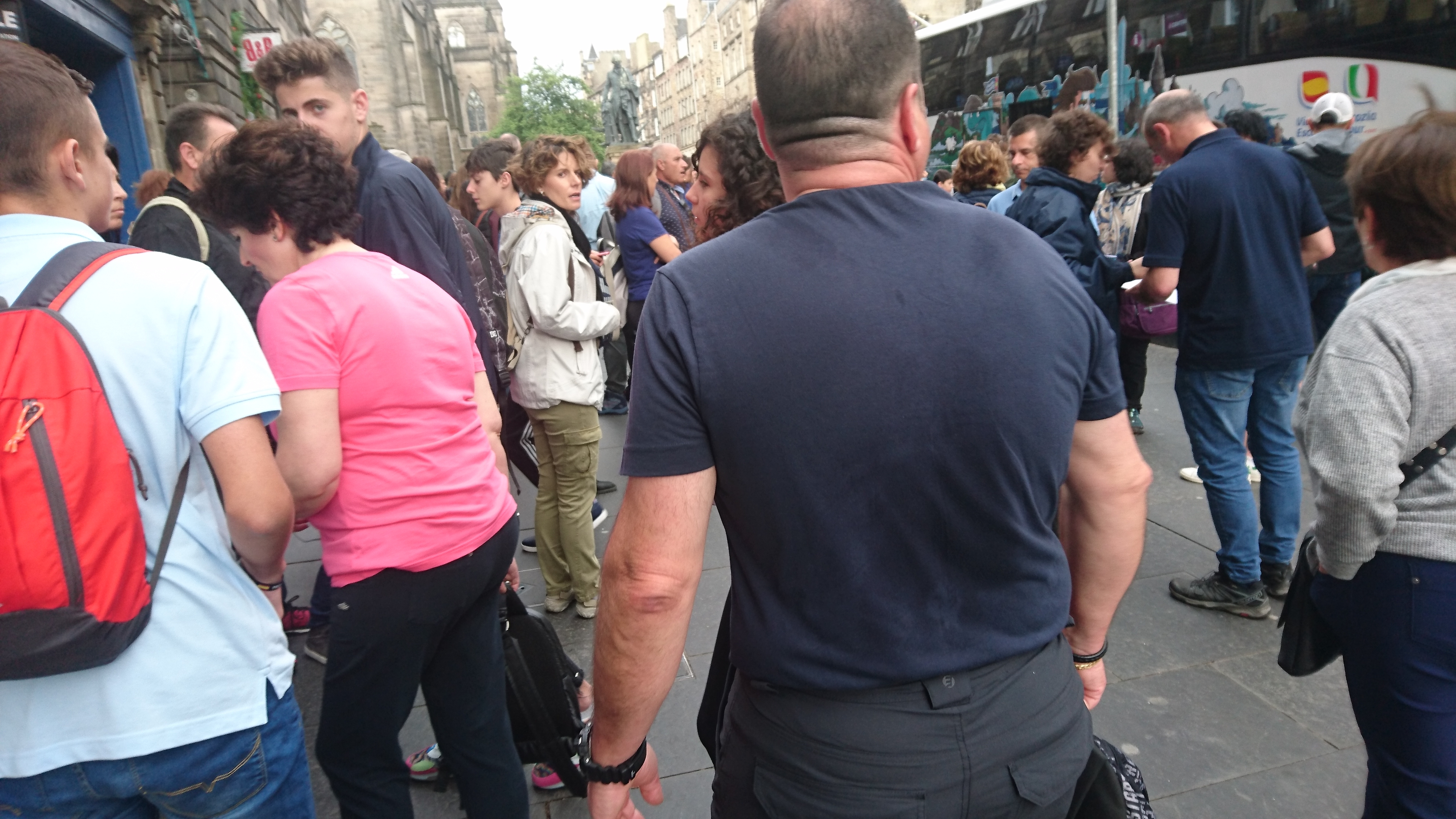 Crowds waiting to board a tourist coach block the street