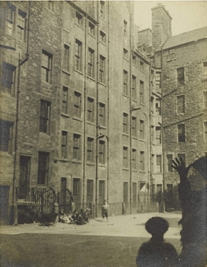 A Francis Chrystal photograph of a dark city court with a boy waving from the side